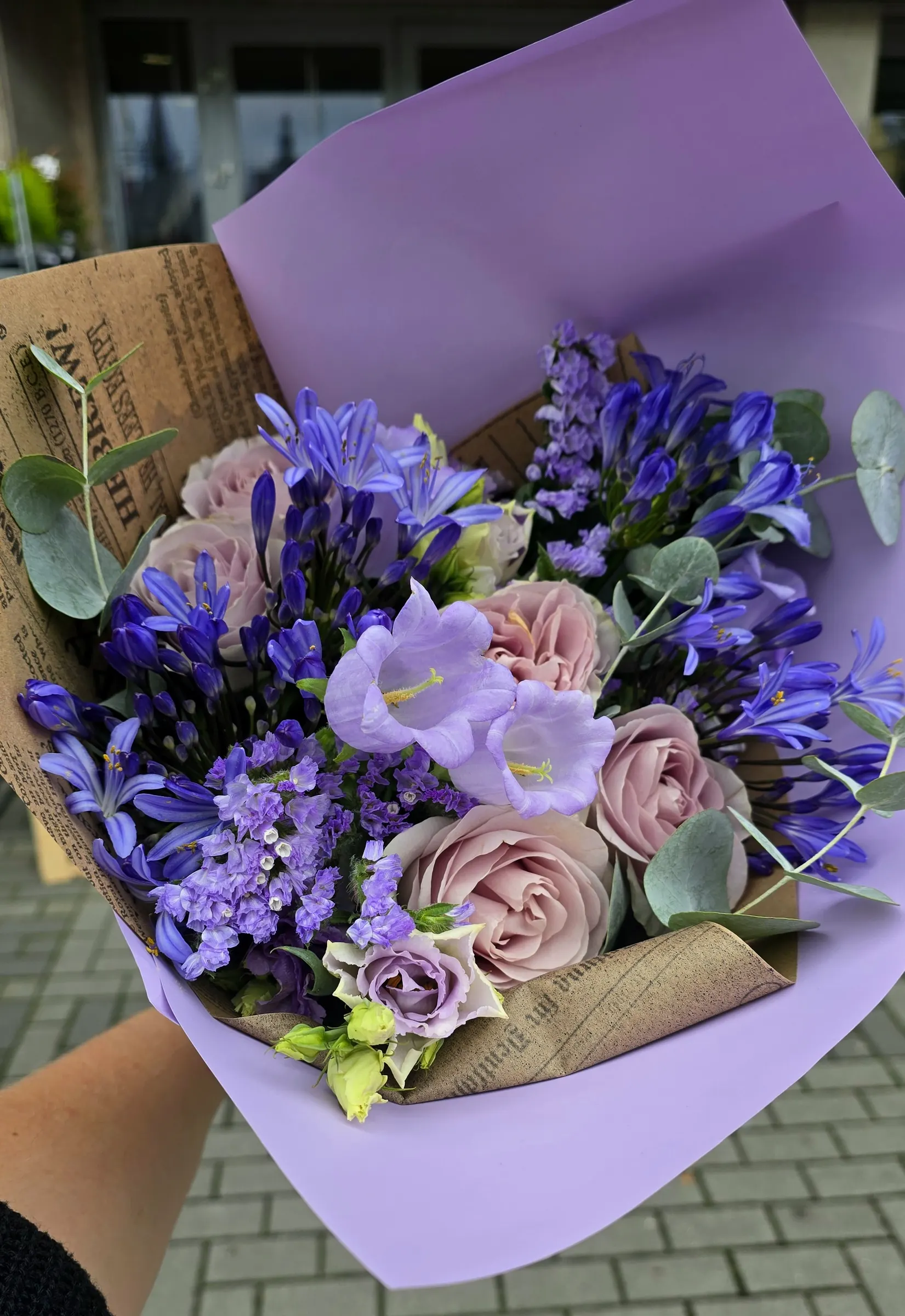Kytice ve fialových a růžových tónech zabalená v šedém papíru